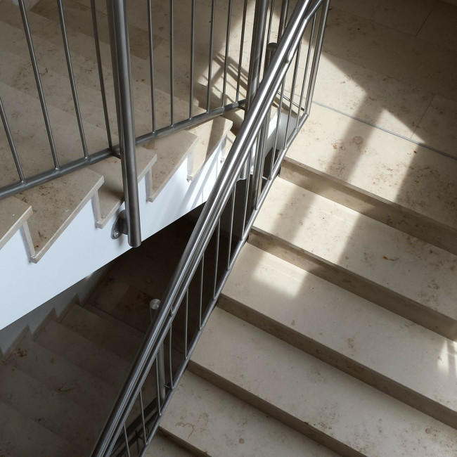 Eine Treppe mit beigefarbenen, marmorierten Treppenstufen. 